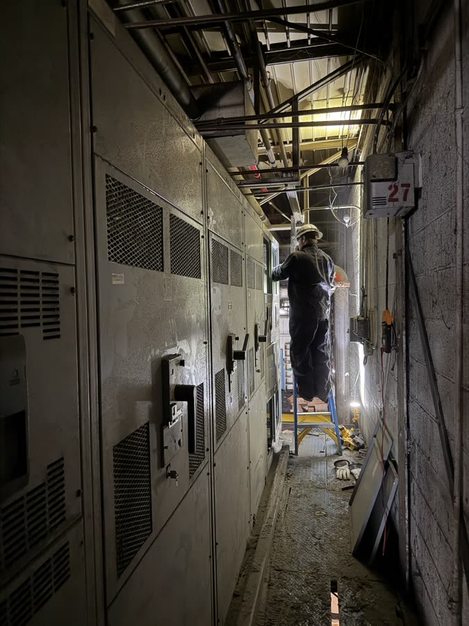 Electrician servicing industrial switchgear at commercial facility